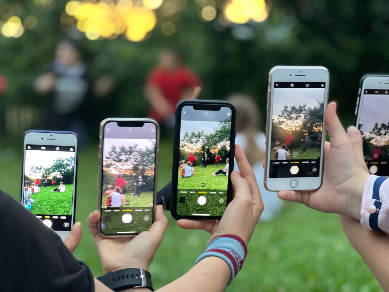 A group of people using smartphones to photograph an outdoor scene.